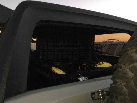1988 Ford Bronco - The open storage box of a vehicle contains yellow items, with another vehicle visible in the distance.