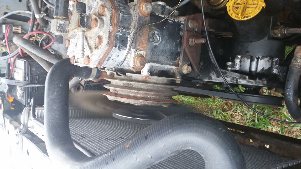 Engine compressor with pulleys and hoses, showing some rust and wear