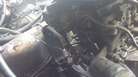 1984 Ford Bronco - Close-up view of an engine's carburetor and linkage system, showing mechanical components and wiring.