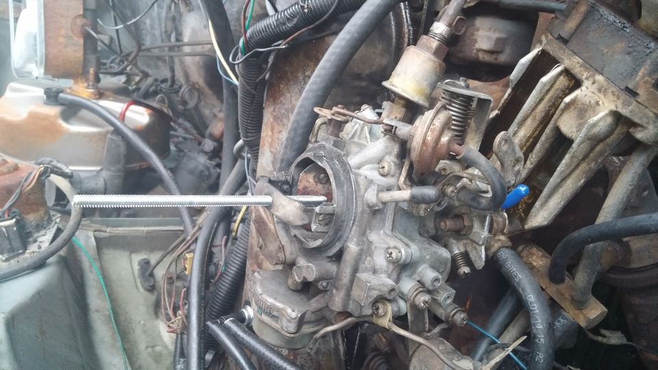 Close-up of a carburetor with various hoses and wires connected to engine components