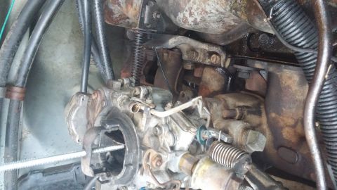 1984 Ford Bronco - Close-up view of an engine's carburetor, showing intricate mechanical parts and signs of wear.