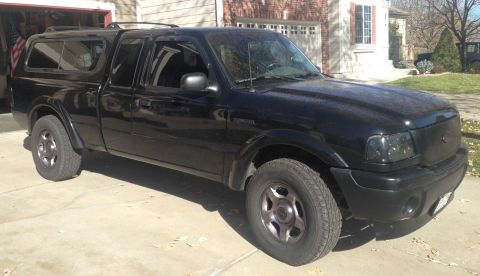 2001 Ford Ranger - A black 2001 Ford Ranger pickup truck with a bed cap is parked in a driveway.