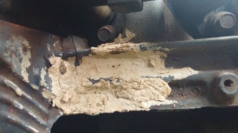 1984 Ford Bronco - Close-up of a corroded engine component with flaking paint.