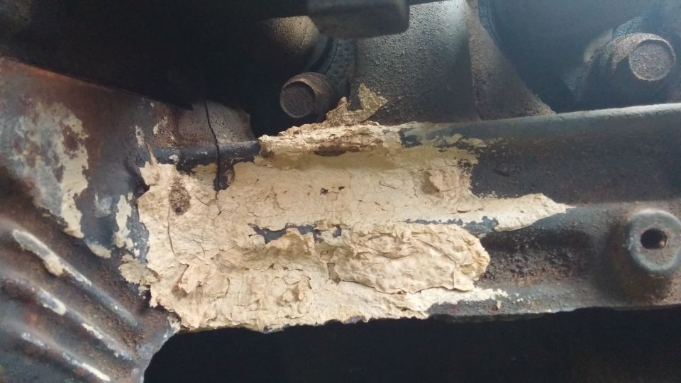 Engine part with peeling beige paint and rust
