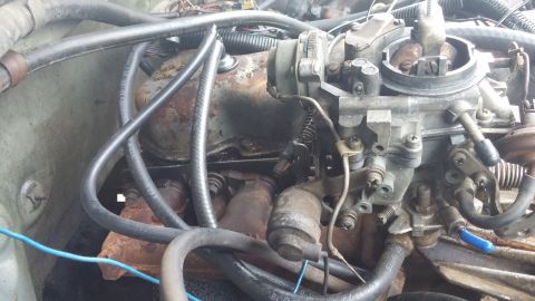 1984 Ford Bronco - This image shows a detailed view of a vehicle's engine compartment, focusing on the carburetor and associated components.