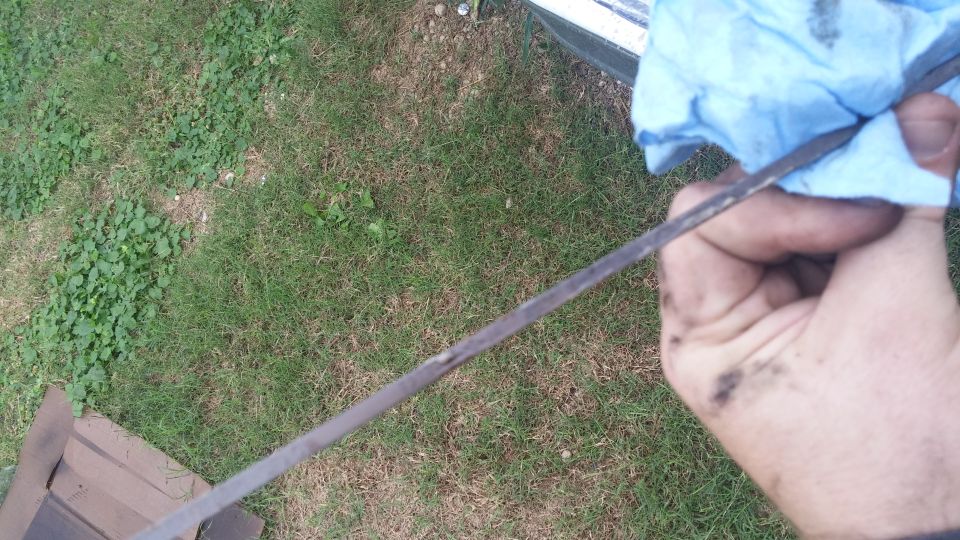 Oil dipstick being checked with a blue rag