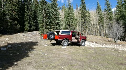 1996 Ford Bronco - Red 1996 Ford Bronco parked in a wooded area with the rear door open.