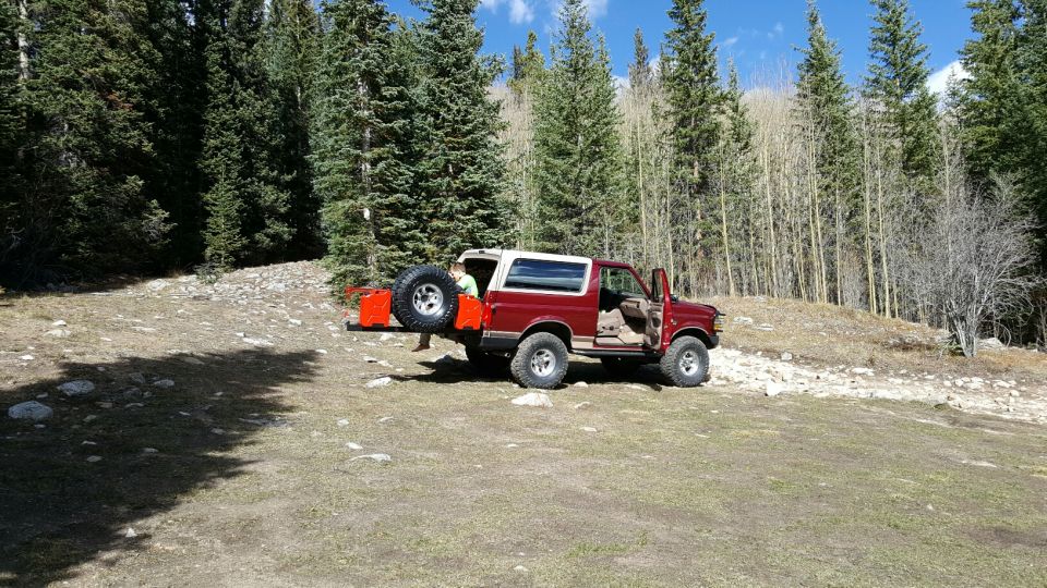 1996 Ford Bronco parked off-road with rear door open and spare tire carrier extended