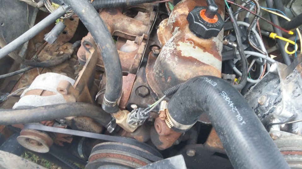 Engine bay with hoses and rusty components. Text on hose reads 10L-24XRS