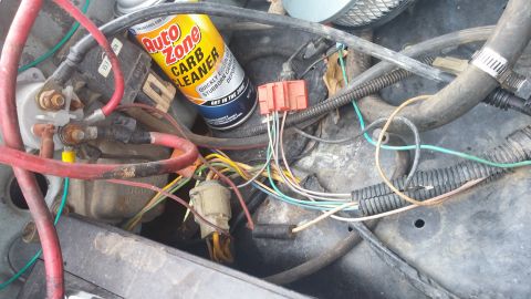 1984 Ford Bronco - A close-up view of a vehicle's engine bay, showing various wires and a can of carb cleaner.