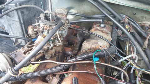 1984 Ford Bronco - Close-up view of a vehicle's engine compartment, focusing on the carburetor and associated components.