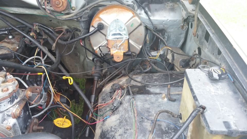 Engine bay showing brake booster, master cylinder, and tangled wiring