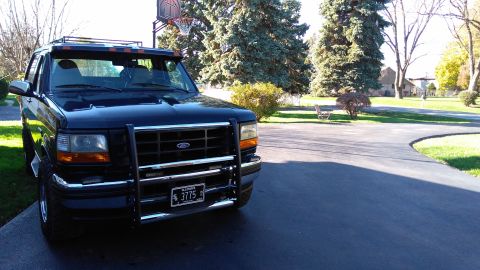 1996 Ford Bronco - This 1996 Ford Bronco features a prominent push bar and a roof rack, seen parked in a driveway.
