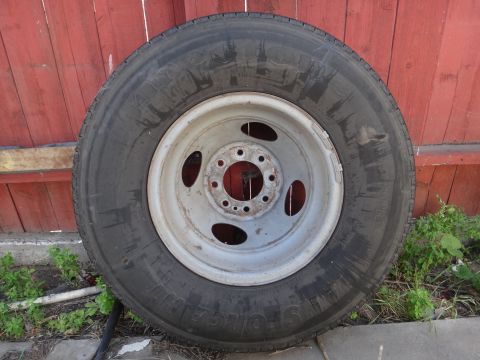 1995 Chevrolet P30 1 Ton - Step Van - A single wheel and tire assembly is shown against a red wooden fence.