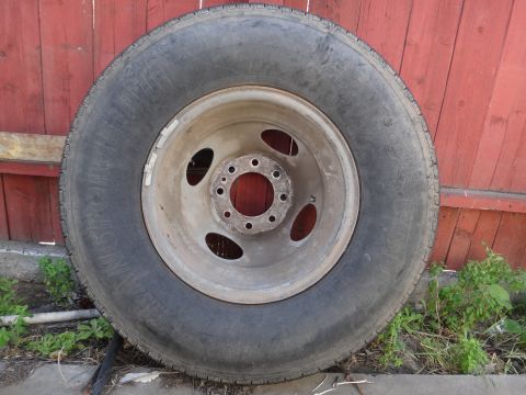 1995 Chevrolet P30 1 Ton - Step Van - A single truck wheel and tire is shown in front of a weathered red wooden fence.