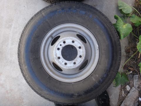 1995 Chevrolet P30 1 Ton - Step Van - A close-up view of a single tire and wheel assembly, with some greenery in the background.