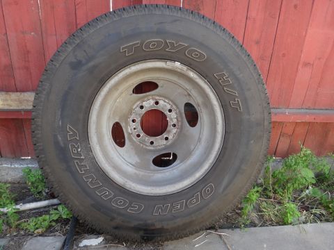 1995 Chevrolet P30 1 Ton - Step Van - A single tire and wheel assembly is shown against a wooden fence.