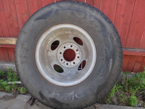 1995 Chevrolet P30 1 Ton - Step Van - A single tire and wheel assembly is shown against a red wooden fence.