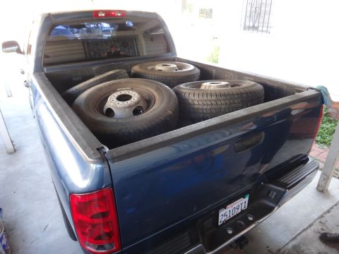 1995 Chevrolet P30 1 Ton - Step Van - The rear of a blue pickup truck is shown with four tires and wheels loaded in the bed.