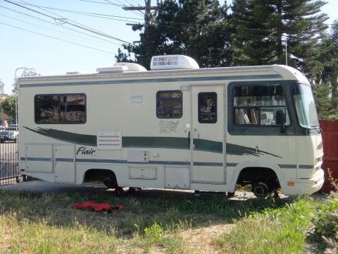 1995 Chevrolet P30 1 Ton - Step Van - RV with 'Flair' graphics parked outside, missing front wheels.