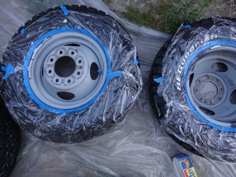 1995 Chevrolet P30 1 Ton - Step Van - Two wheels and tires are prepared for painting, covered in plastic wrap and secured with blue painter's tape.
