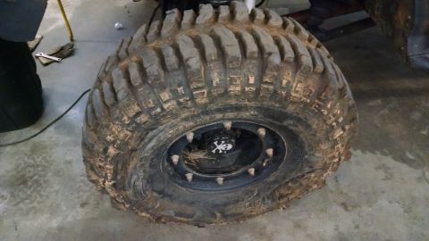 1995 Ford Bronco - A close-up of a heavily used off-road tire, showing mud and a skull-themed center cap.