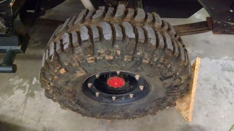 1995 Ford Bronco - A close-up view of a large, mud-caked off-road tire and wheel assembly.