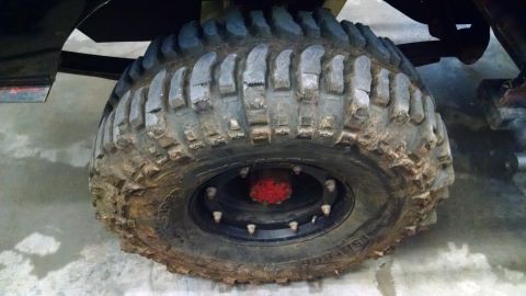 1995 Ford Bronco - A close-up view of a off-road tire and wheel assembly, aggressive tread and a prominent red hub.