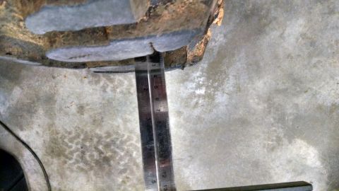 1995 Ford Bronco - A ruler is used to measure a gap on a vehicle's suspension component, likely for modification or repair.