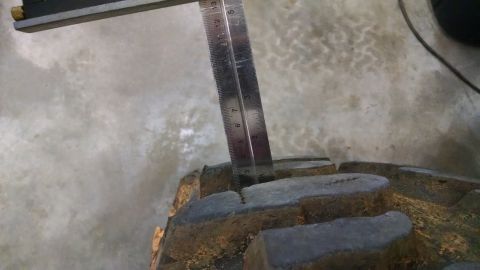 1995 Ford Bronco - Tire tread depth is measured with a ruler, indicating wear on the tire.