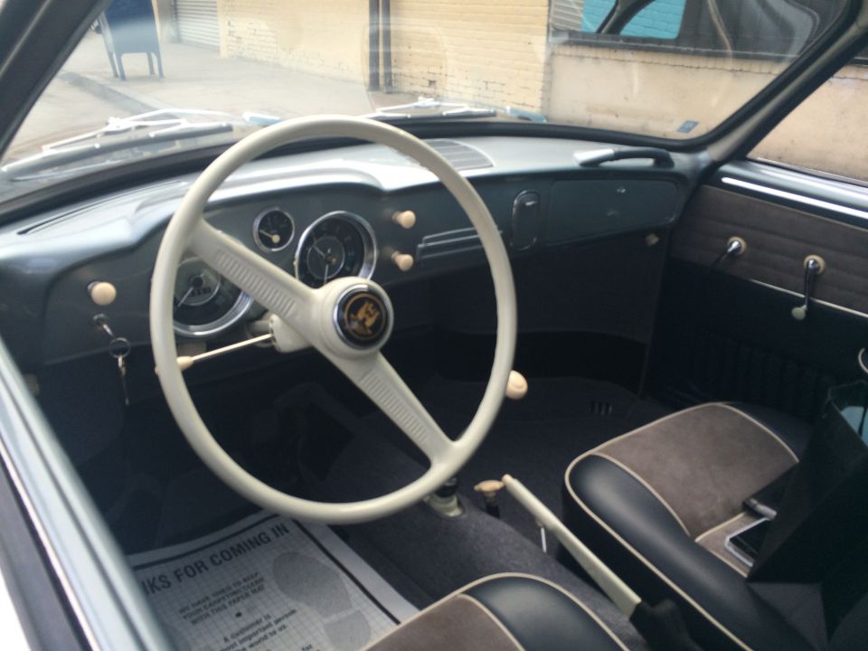 Car interior with a white steering wheel, dashboard gauges, and two-tone seats