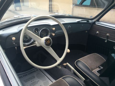 1968 Ford Mustang - The interior of a classic car features a white steering wheel and dashboard, with a floor mat displaying text.