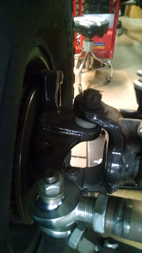 1985 Jeep CJ7 - A close-up view of the suspension and steering components of a vehicle, including a tire, brake rotor, tie rod end, and ball joint. The par…
