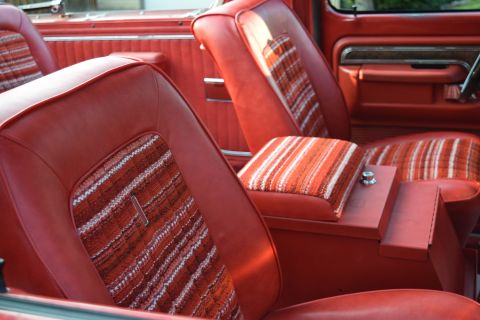 1978 Ford Bronco - The interior of a vintage Ford Bronco features red vinyl seats with patterned fabric inserts on the seat bottoms and seat backs. A red cent…