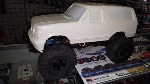 1996 Ford Bronco - An RC crawler wearing an unpainted white hard body shell styled after a full-size Bronco-type SUV, sitting on a glass hobby-shop counter ov…