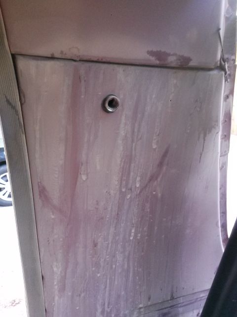 1996 Ford Bronco - A close-up view of the interior panel of a vehicle, showing a metal grommet or fastener. The panel appears to be a light purple or pinkish-…
