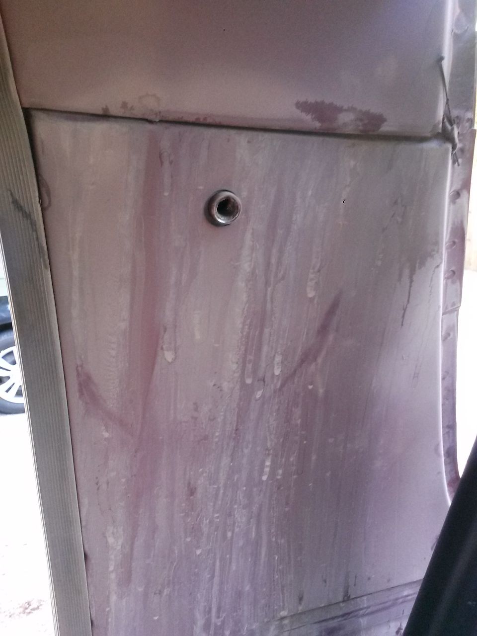 Interior vehicle panel with a metal grommet, showing streaks and water marks.