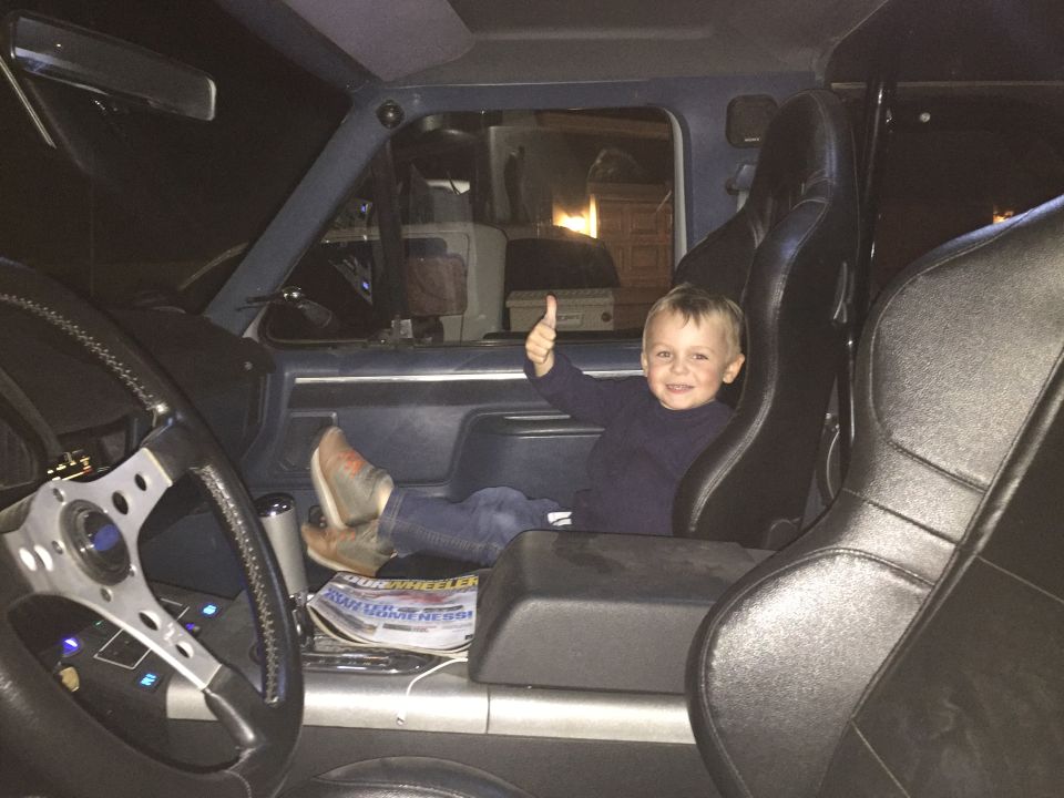 Kid giving thumbs up inside a vehicle, sitting in the passenger seat
