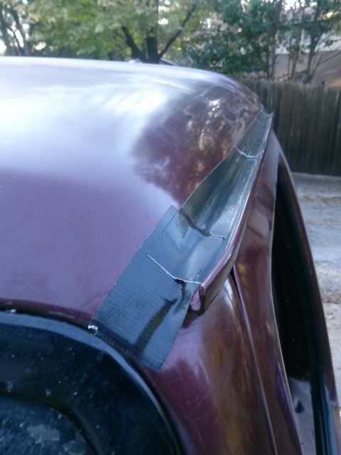 1996 Ford Bronco - A close-up view of a car's roof drip rail, showing a repair made with black duct tape.