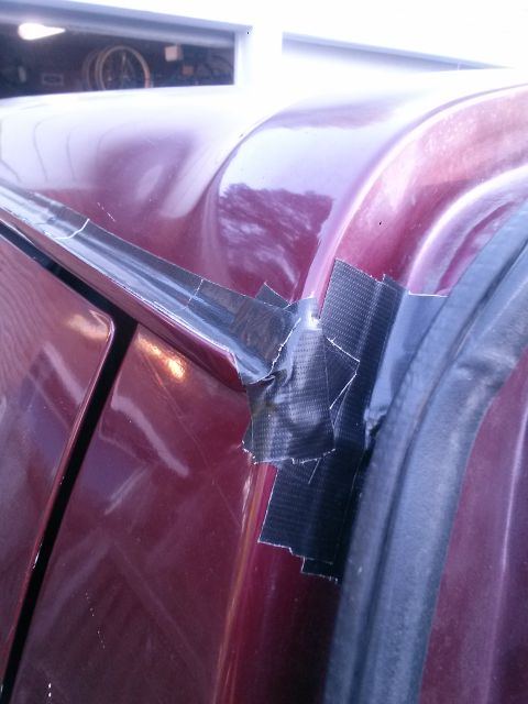1996 Ford Bronco - Duct tape is used to secure the drip rail on this maroon vehicle.