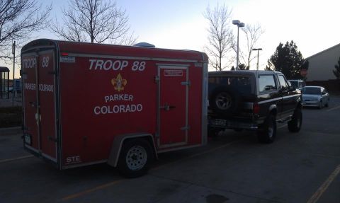 1996 Ford Bronco - A red enclosed cargo trailer lettered 'TROOP 88 PARKER COLORADO' with a Scout emblem sits in a parking lot hitched behind a dark 1990s Ford…