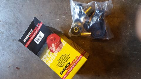 1994 Ford Bronco - A box of Energy Suspension polyurethane components and a bag of black and gold polyurethane bushings and metal sleeves are laid out on a co…