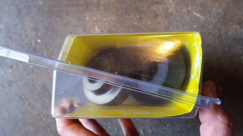 1994 Ford Bronco - A clear plastic package containing two dark-colored, circular parts with white accents is held by a hand. A white label with the letters "E…