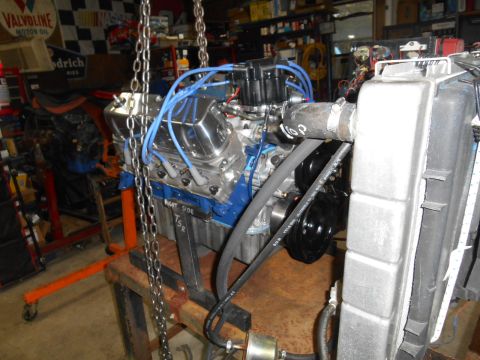 1972 Ford Bronco - A V8 engine, likely a Ford small-block based on the valve covers and distributor, is mounted on an engine stand in a garage setting. The en…
