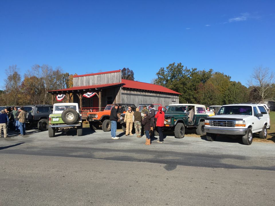 Vintage Ford Broncos and off-road vehicles parked in front of a building.