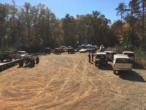 1979 Ford Bronco - A group of off-road vehicles are parked in a dirt lot with trees in the background. Several custom-built buggies and modified trucks are vi…