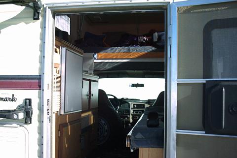 1995 Ford Bronco - View into the interior of a camper van, showing the sleeping area above the cab and the living space with kitchen amenities.
