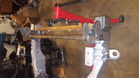 1994 Ford Bronco - A custom metal fabrication is mounted to a red jack stand, with wooden beams and various metal components visible. The fabrication appears…