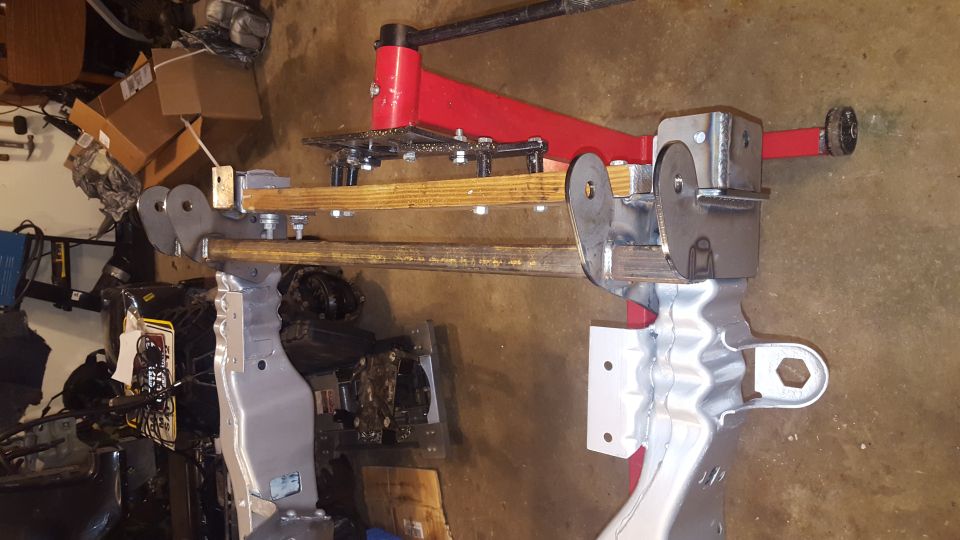 Custom metal fabrication mounted on a red jack stand, possibly part of a vehicle chassis or suspension.