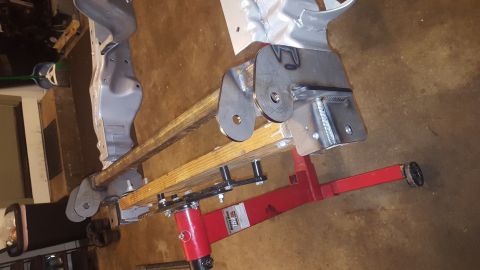 1994 Ford Bronco - A custom fabricated suspension component, likely for a truck or SUV, is mounted on a red engine hoist. The part is made of welded steel and…